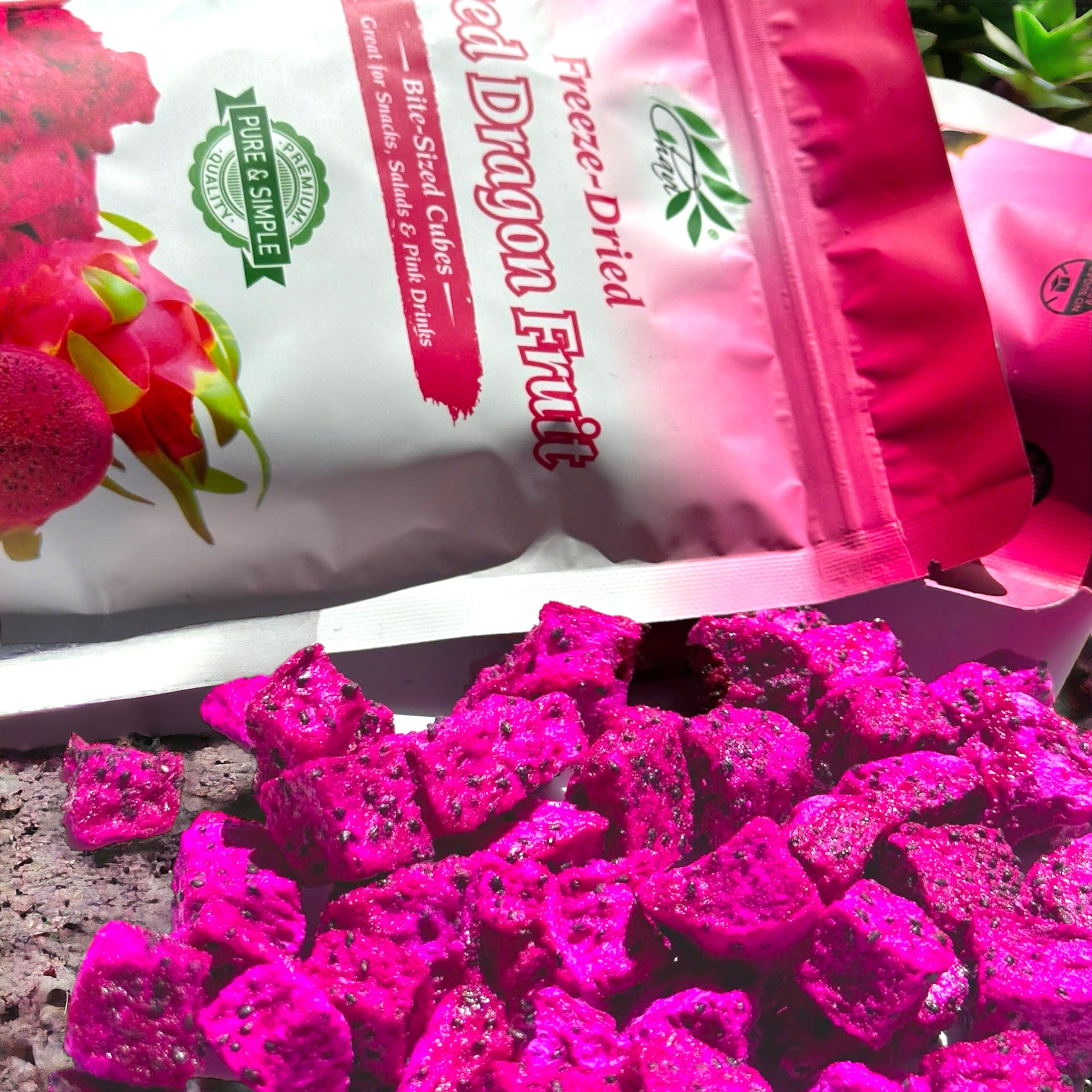 Vibrant pieces of freeze-dried dragon fruit with packaging in the background, showcasing a healthy tropical snack.